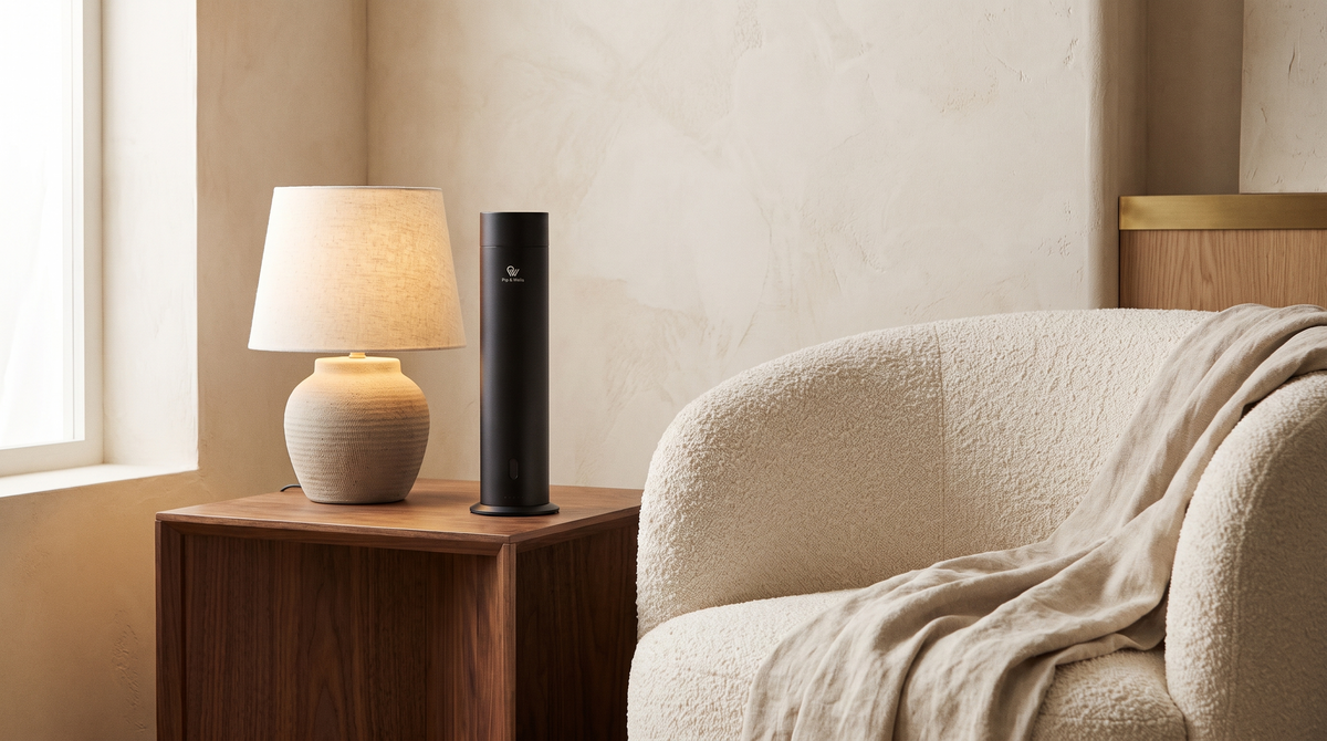 Matte black Pure One diffuser beside a ceramic lamp and boucle armchair in a layered, tactile interior